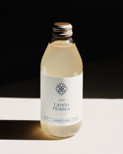 Botella de limonada con etiqueta de Grupo Limón Hoteles sobre fondo oscuro.
