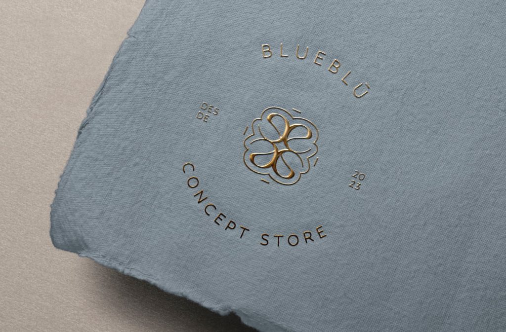 Logotipo circular de Blueblú en foil dorado sobre papel azul artesanal, detalle de branding premium.