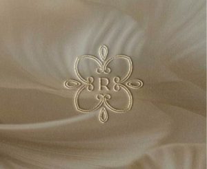 Logotipo dorado en relieve de la marca de papelería para bodas y eventos De la Roo, con diseño elegante y sofisticado.