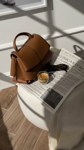 Composición editorial con bolso, gafas y periódico personalizado de Clínica Etérea.